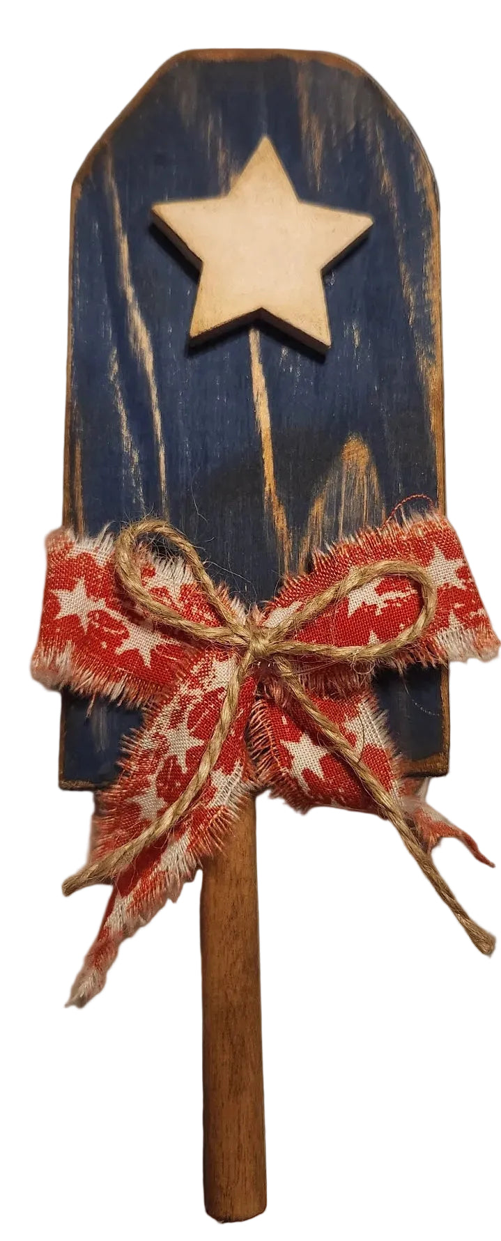 Decorative wooden tool with a star, red and white bow, and cinnamon stick on a beige background