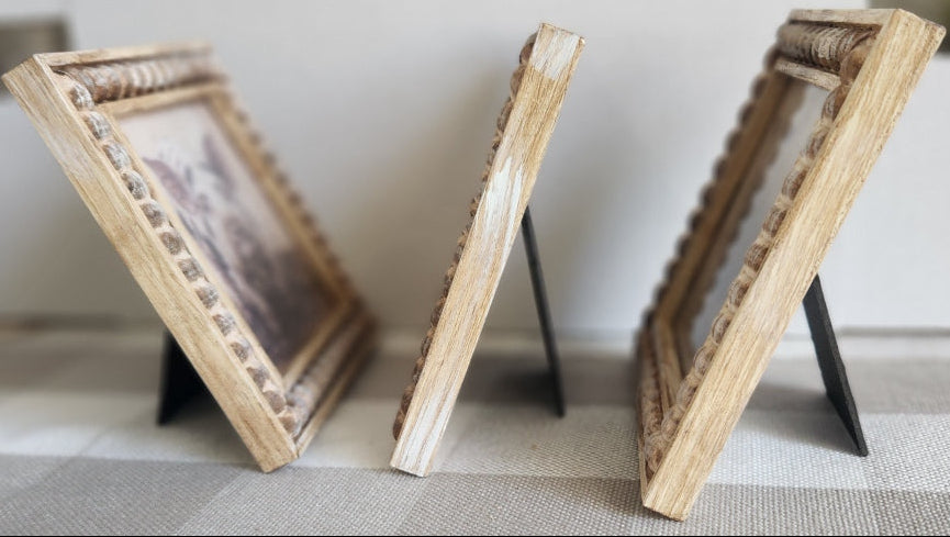 Wooden picture frame holder attached to a wall with a checkered curtain in the background.
