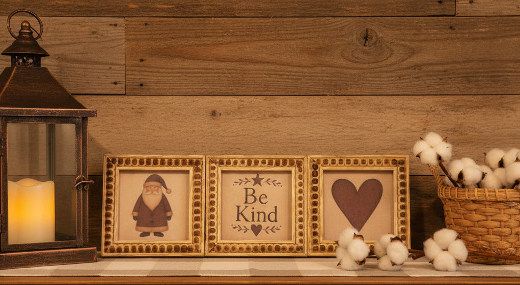 Three decorative picture frames with a Santa Claus, 'Be Kind' text, and heart design on a checkered surface.