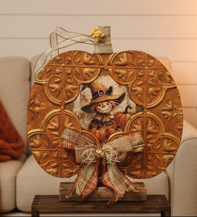 Decorative wall piece with embossed gold design and fabric bow on a white background